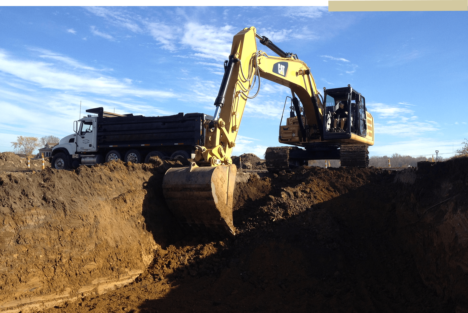 Excavator digging near a dump truck.